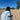 Person on a sandy beach wrapped in a blue and white striped Pouty Paws dog towel with a black dog silhouette